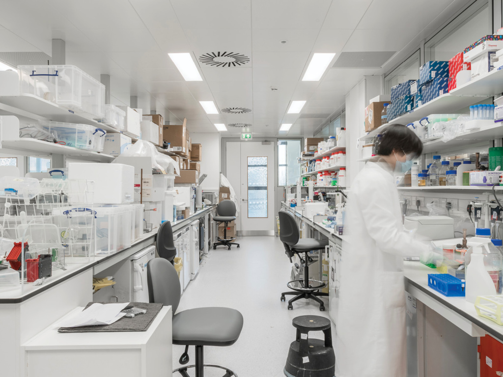 MGAG Institute of Cancer Drug Discovery. A technician works in a bright, busy lab.